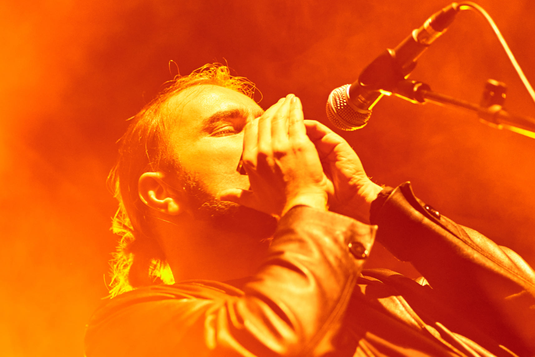 Manlio Milazzi playing blues harmonica under red stage lights